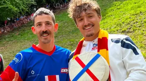 Two men smiling at camera holding cheese