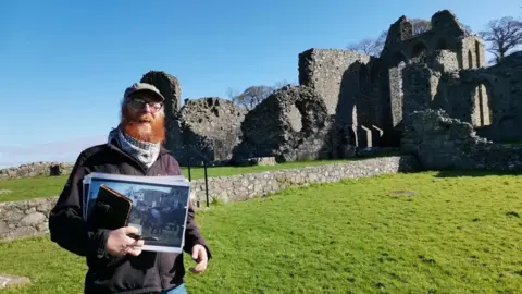 Richard Hodgen Ginger man standing in front of abbey ruins