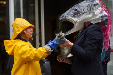 Victoria Jones/PA Media Campaigners from Ocean Rebellion take part in a protest outside the Hilton Hotel, central London, where the Blue Food Innovation Summit is taking place, 21 May 2024.