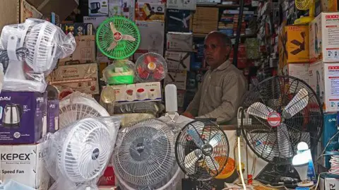 Getty Images A shopkeeper selling table fans waits for customers at a market on a hot summer day in Varanasi on May 27, 2024