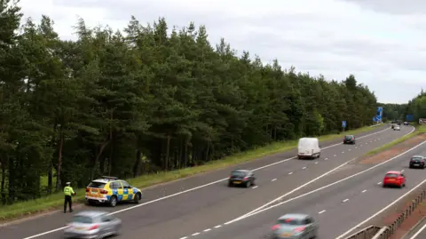 PA Media A police car sits near to Junction 9 of the M9 after a car was discovered