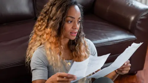 Getty Images A woman looks at bills