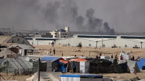 EPA Smoke rises while Palestinians flee camps in the Rafah area amid renewed Israeli strikes and troop advances, in the southern Gaza Strip (28 May 2024)