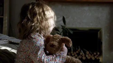 BBC A child holding a teddy bear