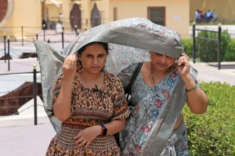 Getty Images Tourists using saree for protection from the scorching sun on a hot summer day, in Jaipur, Rajasthan, India, on Wednesday, May 22, 2024.