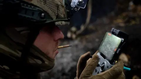 BBC/Lee Durant A soldier smokes as he operates a drone