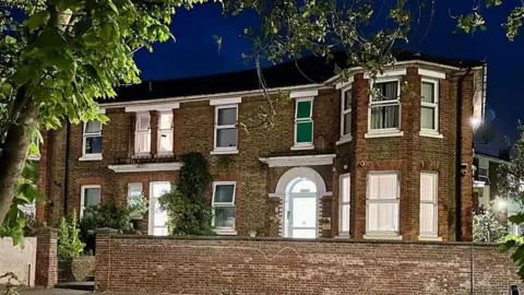 BBC Fleming House, a building converted from a large Victorian house or several houses, pictured as the sky darkens with the windows brightly lit