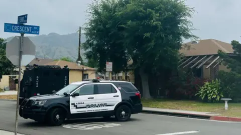 Azusa Police Department/ Instagram Azusa Police Department vehicle on the block of the home were a search warrant was executed