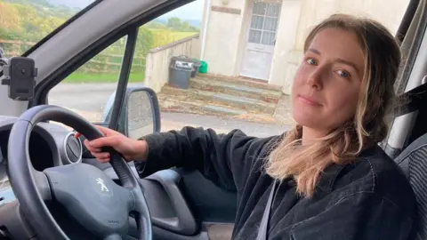 Ellie Rylands Ellie Rylands sitting behind the wheel of her car