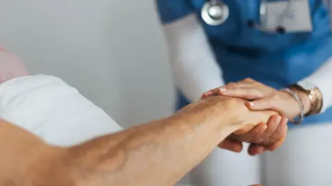 Getty images Nurse and patient holding hands